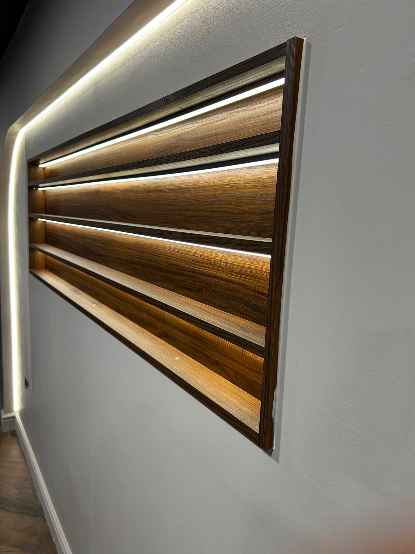 Wall-mounted wood slat panel with warm LED backlighting